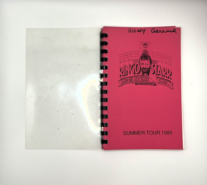 A vintage spiral-bound booklet or program cover for Ringo Starr and the All Star Band summer tour 1969, shown open on a white background. The right page is bright pink with black printed text and a portrait graphic, while the left page is blank white paper.